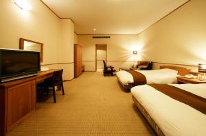 高山市にある中尾高原ホテル 風車のベッド2台、薄型テレビが備わるホテルルームです。