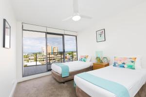 a bedroom with two beds and a large window at Sevan Apartments Forster in Forster