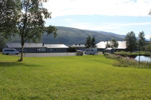 ein Grüngrasfeld mit einem Gebäude und einem Parkplatz in der Unterkunft Sandvik Gjestegård in Sandvik