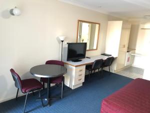 a hotel room with a desk with a television and chairs at Orange Motor Lodge in Orange