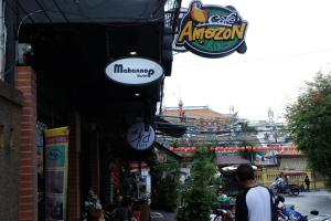 Una calle con gente caminando por una calle con señales en Mahannop Hostel, en Bangkok