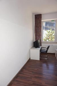 an empty room with a desk with a computer and a window at Artus Hotel in Düsseldorf