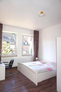 a bedroom with a white bed and two windows at Artus Hotel in Düsseldorf