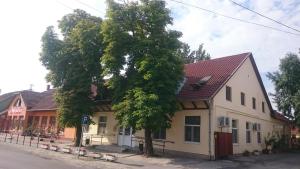 a building with a tree next to a street at Bordany Hostel in Bordány