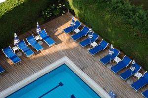 vista sulla piscina con sedie a sdraio di Harvey Suites Hotel & Residence a Lido di Jesolo