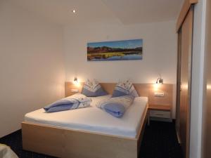 a bedroom with a white bed with blue pillows at Hotel Alpenfrieden in Kappl