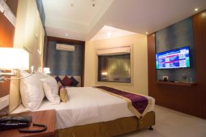 a hotel room with a bed and a flat screen tv at Aura hotel in Kolkata