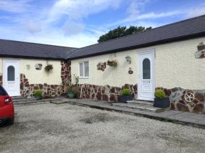 a house with a car parked in front of it at Howard Farm Holiday Cottages in Bude