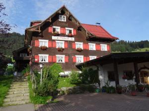 ein großes Gebäude mit roten und weißen Fensterläden in der Unterkunft Landhaus Beate in Hirschegg