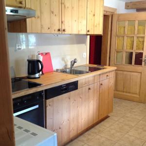 cocina con armarios de madera, fregadero y fogones en Appartement La Croix, en Villarvolard