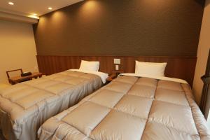2 Betten in einem Hotelzimmer mit Polsterung in der Unterkunft The Base Sakai Higashi Apartment Hotel in Sakai
