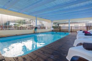 a large swimming pool with white chairs and a blue ceiling at Moon Light Yavneʼel in Yavneʼel