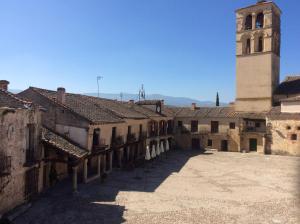 a building with a clock tower and a courtyard at Pedraza Suite in Pedraza-Segovia