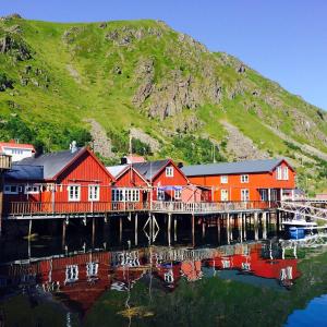a group of red houses on a dock on the water at Kræmmervika Havn in Ballstad