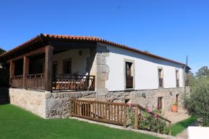 een groot stenen huis met een veranda en een balkon bij Casa Dona Urraca in Vilarinho da Castanheira