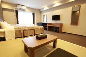 堺市にあるザ ベース 堺東 アパートメントホテルのベッドとテーブルが備わるホテルルームです。
