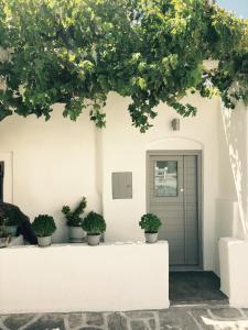a white house with potted plants in front of a door at Naoussa Center Home in Naousa
