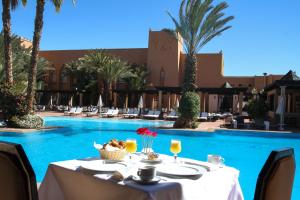 a table with food and drinks next to a swimming pool at Berbère Palace in Ouarzazate