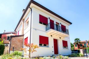 a white building with red shutters on it at B&B La Porta Rossa in Noale