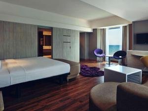 a bedroom with a bed and a living room at Mercure Convention Center Ancol in Jakarta