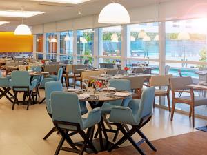 a dining room with tables and chairs and windows at Novotel Rio de Janeiro Parque Olimpico in Rio de Janeiro