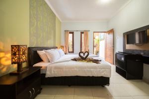 Griya Tunjung Sari في دينباسار: غرفة نوم بسرير وخزانة وتلفزيون