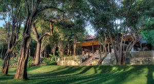 una casa en medio de un patio con árboles en The Deer Park Hotel en Giritale