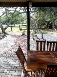 2 bancs en bois assis sur une terrasse dans un parc dans l'établissement Welbedacht Estate Self catering Accommodation, à Port Elizabeth