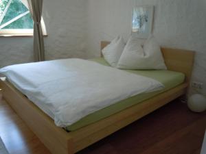 1 cama con sábanas blancas y almohadas en una habitación en Appartementhaus Dargham en Strobl