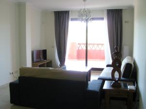 a living room with a couch and a large window at Apartamento del Golf Dona Julia y Cortesin in San Luis de Sabinillas