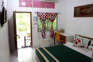 a bedroom with a bed and a desk and a window at Garden Guesthouse in Kampong Chhnang
