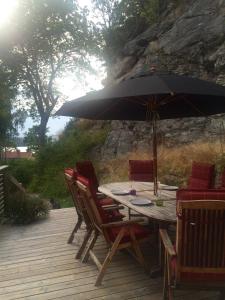 a wooden table with chairs and an umbrella on a deck at Lyckhus in Ljungskile +9 photos