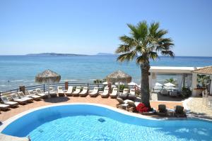 a swimming pool with chairs and umbrellas and the ocean at Delfino Blu Wellness Boutique Hotel in Agios Stefanos