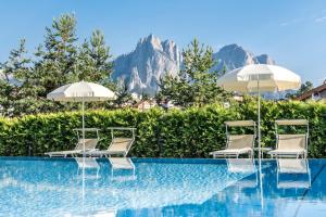 un grupo de sillas y sombrillas junto a una piscina en Hotel Villa Kastelruth, en Castelrotto