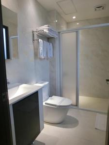 a bathroom with a toilet and a sink and a shower at Happy Hotel in Lugang