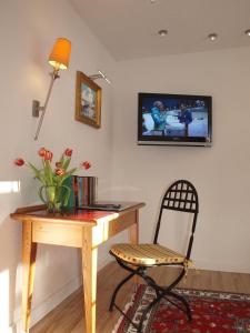 a desk with a chair and a television on a wall at Hotel Hirschen in Menzenschwand