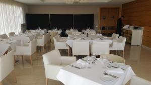 a room with white tables and white chairs and a man at Bahia Golf Beach Apartement in Bouznika