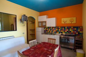 cocina con mesa y cocina con paredes de color naranja en Azzurra Cielomare, en Castellammare del Golfo