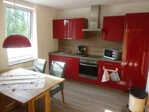a kitchen with red cabinets and a table and a microwave at Welterbe Mittelrhein in Biebernheim