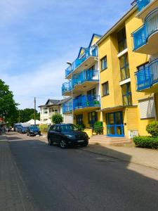ミエンジズドロイェにあるApartament Pomorskaの黄色い建物の前に停まった黒車