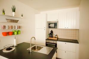 a kitchen with white cabinets and a black counter top at Maison d'O in Ostend