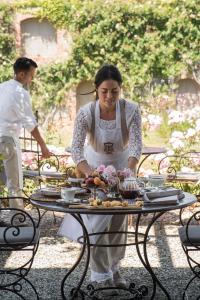 una mujer de pie junto a una mesa con comida en ella en Relais Sant'Elena en Bibbona