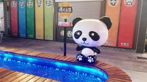 un ours panda assis à côté d'une piscine dans l'établissement Garden Spring Hotel, à Jiaoxi