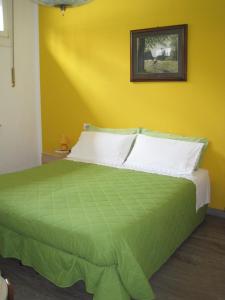 a bedroom with a green bed with a yellow wall at Bed and Breakfast lo Scrigno in Polinago