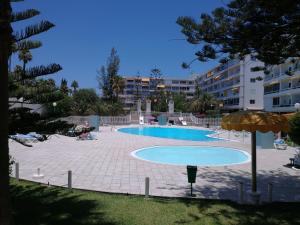 una piscina con sombrilla y algunos edificios en Aloe New Excellence, en Playa del Inglés