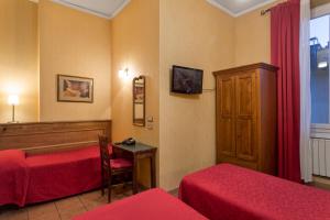 a room with two beds and a desk and a window at Hotel Kursaal & Ausonia in Florence