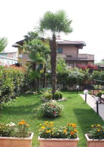 un giardino con fiori e palme e un edificio di Mi Casa Affittacamere a Osio Sotto