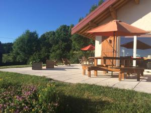 a patio with a table and an umbrella at Au Charnet in Les Fourgs