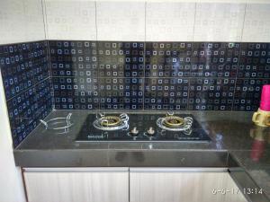 a stove top in a kitchen with a tile wall at PCB Homestay in Kota Bharu