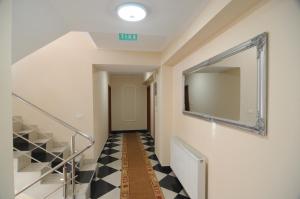 a hallway with a mirror and a checkerboard floor at Pensiunea Elisei in Timişoara +16 photos
